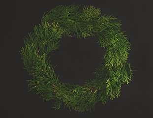 Christmas decorative wreath  with ornament  on black background. Made from thuja, flower, pine cones. Floral design. Festive mod. © NATALIA DAVIDOVA