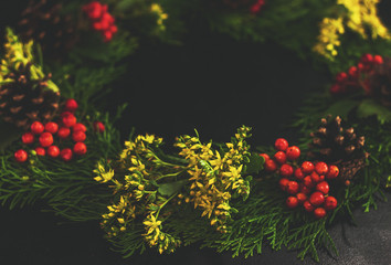 Christmas decorative wreath  with ornament  on black background. Made from thuja, flower, pine cones. Floral design. Festive mod.