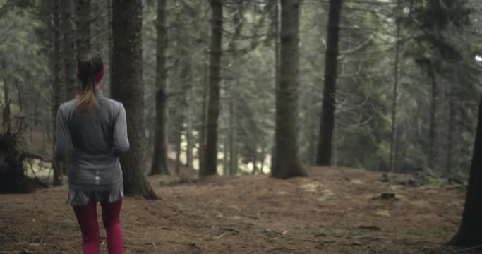 Athlete girl running through forest woods.Following behind.Real people woman runner sport training in autumn or winter in wild mountain outdoors nature, bad foggy weather.4k 60p slow motion video