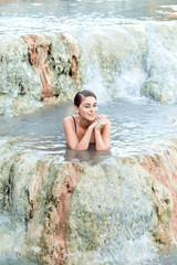 Fototapeta na wymiar Pretty young brunette woman taking a bath in the natural thermal waters of spa, Saturnia Italy