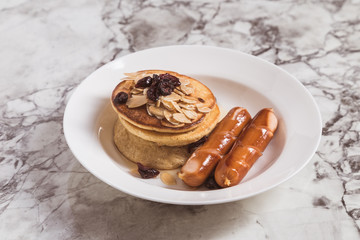 Breakfast Pancake and Sausage Top with Almond and Raisin on white plate