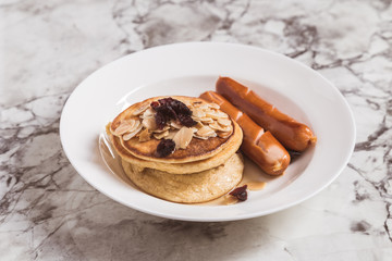 Breakfast Pancake and Sausage Top with Almond and Raisin on white plate
