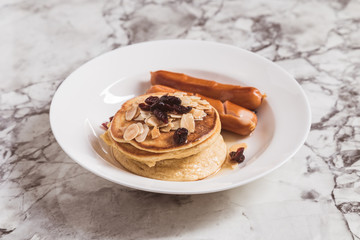 Breakfast Pancake and Sausage Top with Almond and Raisin on white plate