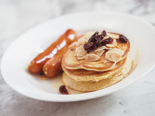 Breakfast Pancake and Sausage Top with Almond and Raisin on white plate