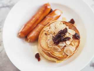Breakfast Pancake and Sausage Top with Almond and Raisin on white plate