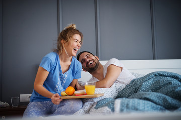 Beautiful happy young romantic girl brings breakfast to her husband in the bed and laughing...