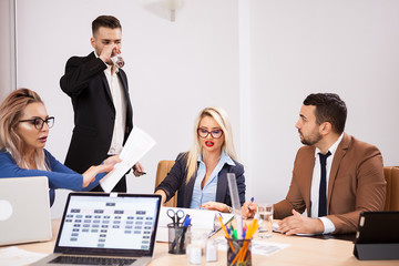 Creative Team of business people at meeting in the conference room. Two successful business women and two businessmen at the desk. They are discussing new projects