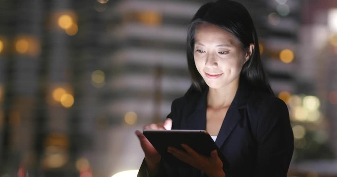 Businesswoman working on tablet computer at night