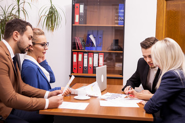 Team of four business people in office talking and working on new projects