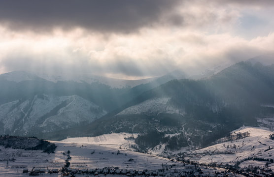 sunbeams through clouds over the snowy mountains. beautiful countryside scenery in winter