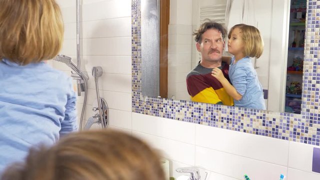 Father with daughter and son dancing in front of mirror in bathroom having fun