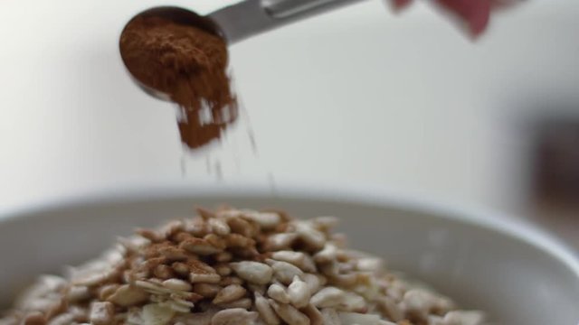 Closeup Of Woman Sprinkling Spoonful Of Cinnamon Onto Bowl Of Granola, Slow Motion, 4K 