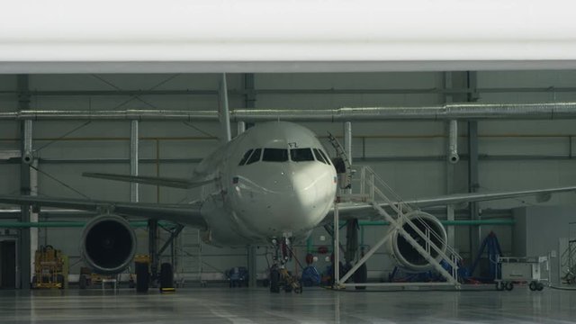 Roller shutter door and plane in hangar background. Business jet airplane is in hangar. Private corporate jet parked in a hangar facing away from the camera towards the doors in an aviation