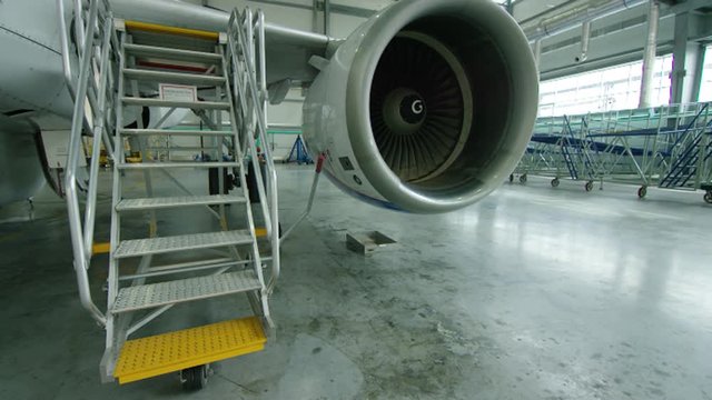 Aircraft engine in the hangar. Airplane turbine detail, plane in hangar. Engine of the airplane under heavy maintenance