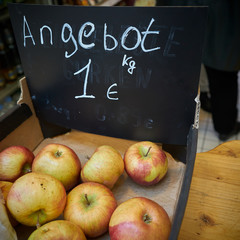 Äpfel auf einem Marktstand. Im Hintergrund ein Schild mit der Aufschrift 
