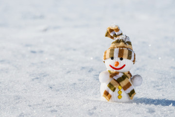 A snowman in striped knitted hat and scarf on snow white background