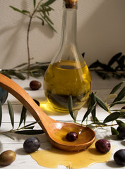 Grüne und schwarze Oliven mit einem Holzlöffel mit Olivenöl und einer Flasche