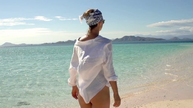 Attractive woman walking on the beautiful beach, steadycam shot, slow motion shot at 240fps
