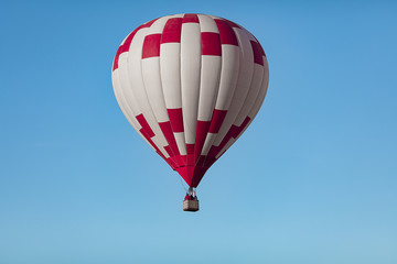 red white hot air balloon in the cloudless blue sky closeup