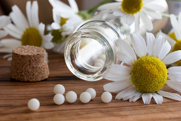 A bottle of homeopathic globules with chamomile flowers