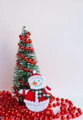 Merry Christmas greeting card with snowman and christmas tree  with red garland on white background.