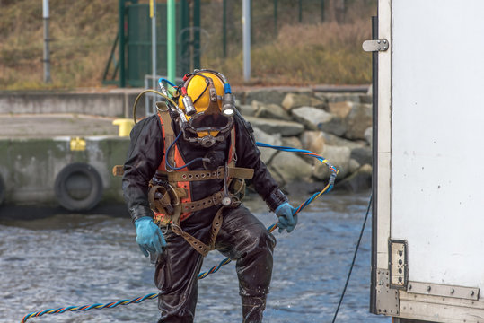 A diver with diving helmet searches for garbage on the harbor bottom in the harbor. He finds a bike thatis heavily covered with algae and shells and covered with seaweed. Keep our sea lake and river