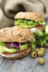 Sandwiches with avocado, camembert, vegetable salad and salami. Breakfast on the rustic table.
