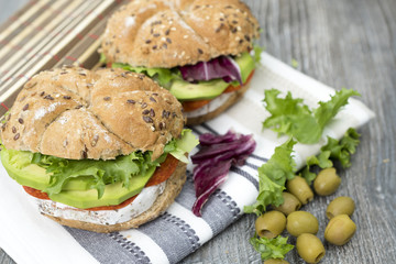 Sandwiches with avocado, camembert, vegetable salad and salami. Breakfast on the rustic table.