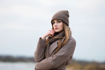 girl in a knitted cap and scarf in the autumn on nature. cold.