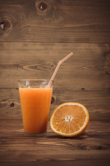 Orange juice in glass and fresh fruits on wooden background