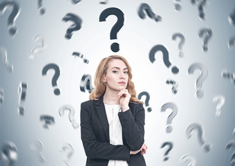Pensive red haired businesswoman, question marks