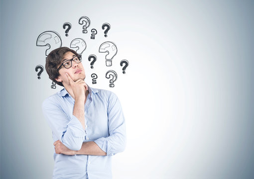 Pensive young man in glasses, questions