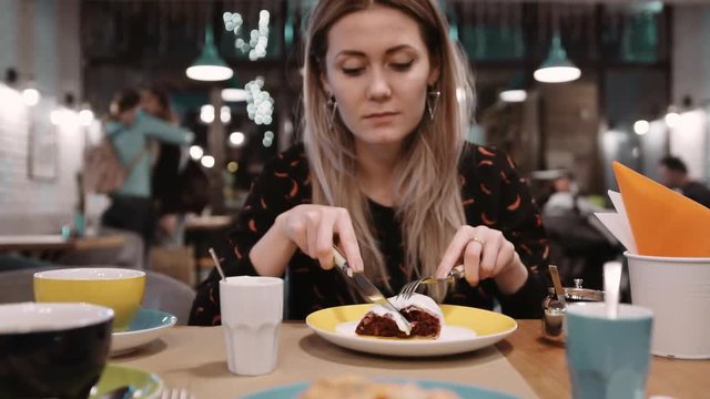 Woman eating dessert strudel at the restaurant using fork and knife. Slow motion.