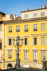 Fototapeta na wymiar Bright yellow facade with traditional street lamp post - taken in Florence, Tuscany, Italy