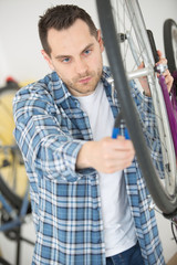 Fototapeta na wymiar man fixing wheel of bike in his workshop