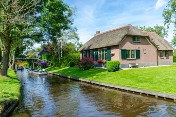Fototapeta na wymiar Giethoorn, Netherlands: View of famous Giethoorn village with canals and rustic thatched roof houses.The beautiful houses and gardening city is know as 
