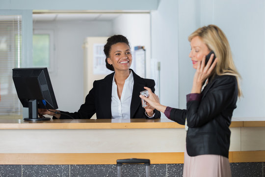 friendly hotel receptionist handing over key to customer