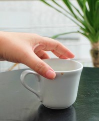 Hand Holding Empty Cup of Coffee on The Table