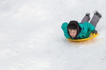 Fototapeta na wymiar Boy sledging down hills winter