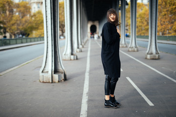 Fashion beauty woman in black coat walking on the street in Paris