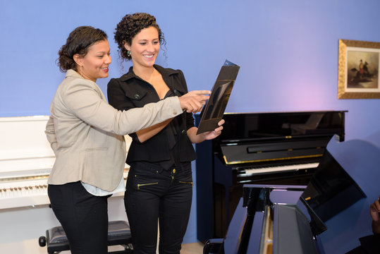Women with pianos looking at folder