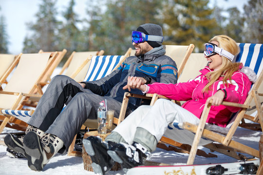 Couple in love resting from skiing in sun lounger