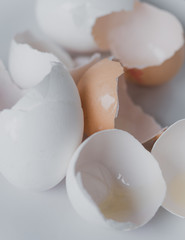Empty, cracked and broken open egg shells of white and brown chicken eggs with leftover egg white...