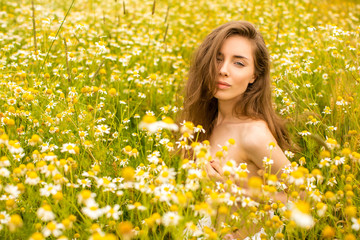 Sexy brunette young woman in chamomile field