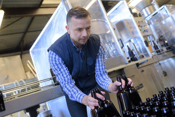 brewer holding beer bottles in crate at brewery