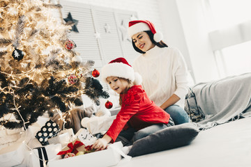 Obraz premium Holidays tradition,Preparation for Christmas. Mother decorating fir tree and room with her daughter. Family at home