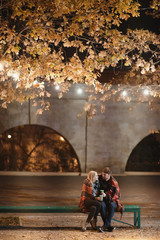 An attractive couple in love embrace and enjoy an intimate moment together, against the backdrop of city lights