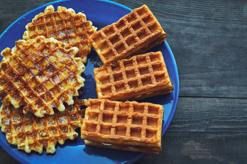 Belgian waffles with honey on blue plate.