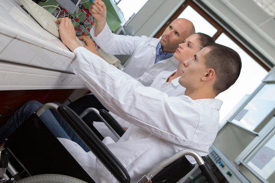 young man on wheelchair and woman in laboratory