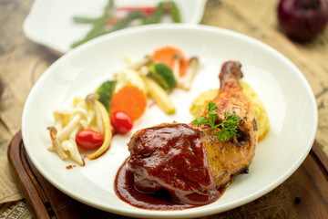 Grilled chicken legs and vegetables in white dish isolated on white plate